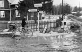 Lantbrevbärare, postiljon Erik Bergman (cykelåkande) i
Delsbo.  April 1956.

Brevbäringsturen är 2 ½ mil lång och omfattar nästan 300 hushåll. Postväskan väger ofta 30-40 kg.