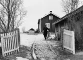 Lantbrevbärare, postiljon Erik Bergman (cykelåkande) i
Delsbo.  April 1956.

Brevbäringsturen är 2 ½ mil lång och omfattar nästan 300 hushåll. Postväskan väger ofta 30-40 kg.