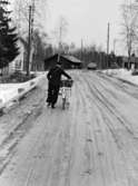 Lantbrevbärare, postiljon Erik Bergman (cykelåkande) i
Delsbo.  April 1956.

Brevbäringsturen är 2 ½ mil lång och omfattar nästan 300 hushåll. Postväskan väger ofta 30-40 kg.