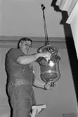 Antikvarisk storstädning på Gunnebo slott 1992. Tekniker Alf Garthman står på en stege och håller en taklampa i händerna.