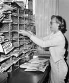 Brevbärarbiträdet fru Valborg Jansson förbereder
brevbäringsturen, på postexpeditionen i Åkersberga.  Augusti 1961.