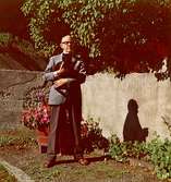 Vidar Karlsson står utomhus med en katt i famnen.