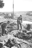 Helmer Garthmans kompis Elon Sävström (till höger) bygger sitt nya hus i Toltorpsdalen på Salfjällsgatan. Helmer hjälper till med schacktning för hand. 1950-tal.