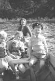 Familjerna Lopez och Garthman i en båt. Stensjön, 1950-tal. Främre rad från vänster: Angela Lopez och Leif Garthman. I mitten: Astrid Garthman med Robert Lopez i knät, Alf Garthman och Gurlie Lopez.