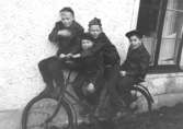 Fyra killkompisar som poserar på en cykel vid Barnhemsgatan 21 ungefär 1957-1958. Från vänster: Roger Karlsson, Alf Garthman, Sune Johansson och Lennart Hedberg.
