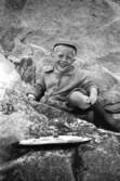 Alf Garthman sitter och leker med sin leksaksbåt bland klipporna vid Näset, 1953-54.