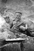 Alf Garthman sitter och leker med sin leksaksbåt bland klipporna vid Näset, 1953-54.