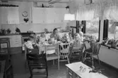 Britt Johansson samt dagisbarn sitter runt köksbordet och äter på Hoppetossan, Katrinebergs daghem, 1992-93.