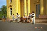 En orkester, bestående av sju män, spelar musik inför publik på Gunnebo slotts framsida.
