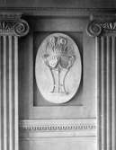 I en tablett, en stående oval relief med emblemet 