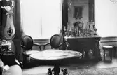 Möblerat rum med antika möbler. I bakgrunden ser man två fönster. Gunnebo slott.