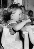 En flicka som äter mat på Holtermanska daghemmet 1953