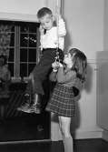 Två barn leker med en trapets hängande från taket vid Holtermanska daghemmet 1953.