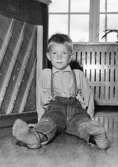 En pojke som sitter på golvet vid Holtermanska daghemmet 1953.