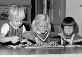 Tre flickor som hjälps åt med ett pussel. Holtermanska daghemmet 1953.
