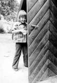 Ett barn står i dörröppningen till ett litet hus. Holtermanska daghemmet 1973.