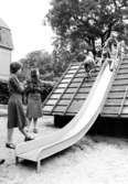 Barn åker rutschbana och två fröknar håller koll. Holtermanska daghemmet 1973.