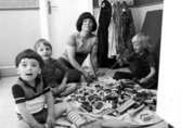 Tre barn och en fröken som sitter på golvet och leker. Holtermanska daghemmet, okänt årtal.