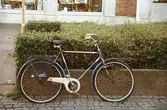 En parkerad herrcykel som har punktering. Mölndalsbro i dag - ett skolpedagogiskt dokumentationsprojekt på Mölndals museum under oktober 1996. 1996_1116-1134 är gjorda av högstadieelever från Kvarnbyskolan 9C, grupp 6. Se även 1996_0913-0940, gruppbilder på klasserna 1996_1382-1405 samt bilder från den färdiga utställningen 1996_1358-1381.