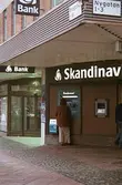 Skandinaviska Enskilda Banken och en Bankomat i hörnet av Brogatan/Nygatan. Mölndalsbro i dag - ett skolpedagogiskt dokumentationsprojekt på Mölndals museum under oktober 1996. 1996_1190-1211 är gjorda av högstadieelever från Kvarnbyskolan 9D, grupp 4. Se även 1996_0913-0940.