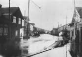 Översvämning i Mölndal, 1930-tal. Från vänster ses Kungsbackavägen 2 samt Göteborgsvägen 1 och 3. 
På andra sidan vägen ses spårvagnsstallarna (hörnet mellan Göteborgsvägen och Kvarnbygatan) samt bankhuset på Kungsbackavägen 1. 
(Hantverkshuset är ännu inte byggt, det uppfördes 1932.)