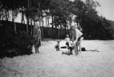 Två män, en kvinna och tre barn på en sandstrand, troligtvis vid Tulebosjön, 1930-tal.
