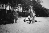 Två män, en kvinna och tre barn på en sandstrand, troligtvis vid Tulebosjön, 1930-tal.
