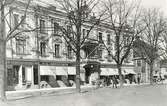 Skara, postkontor.  Den s.k. Assbeckska byggnaden (f.n.
tillhörande Skaraborgs Enskilda Bank), där postkontoret var inrymt
till vänster om huvudingågen under mitten av 1890-talet.  Foto
1920-talet.