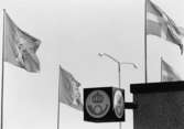 Invigning av postkontoret och Skärholmens Centrum söndagen den 8
sept 1968. Foto 8 sept 1968. Postkontorsskylten - kubformad - ovanför
postkontorsentrén, omgiven av svenska flaggor och Stockholms stads
flagga med S:t Eriks bild.