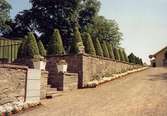 En stenmur runt Gunnebo slott samt en blomkruka på varje sida av muren, juli 1991.