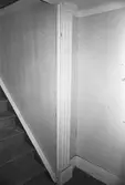 Kvarnfallet 31, röda huset, G-3, hösten 1994. Interiör från Röda husets undervåning. Bilden visar del av förstugan och trappan till övervåningen. Ornerade pilastrar var vanligt förekommande inom den s.k schweizerstilen som i Sverige uppfattades som urnordisk och därför gärna efterliknades i arkitekturen. Man trodde att stilens former uttalade ett nordiskt arv vilket eftersöktes under 1800-talet. En dörr har tidigare funnits för trappuppgången.