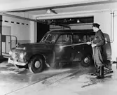 Ett av posttransportörernas dagliga jobb är bilvård under en
halvtimme. Chaufför Einar Andersson spolar här lantbrevbärare Nils
Liberts blå Volvo herrgårdsvagn i postkontorets Eskilstuna 1 garage.