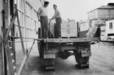 Pallarna med tidningsbuntarna körs över till en lastbil, vid
ICA-Kurirens lastbrygga, f.v.b. till järnvägen.