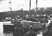 Skutan Venus lägger till med 852 flyktingar ombord. Båten som familjen Karisaar kom med från Finland år 1944, lägger här till i Örnsköldsvik. Några timmar tidigare hade båten varit nära att gå i kvav mot klipporna utanför Ulvön. Passagerarna var både trötta, frusna och hungriga. Fem personer ombord hade dött under den mardrömsliknande överresan. Hösten 1944 flydde 32.000 estländare från kriget i Estland till Sverige. Ett sextiotal personer tog jobb på August Werners textilfabrik i Lindome. 
Kvinnorna arbetade i spinneriet och männen i färgeriet.
Mer information finns i uppsatsen 