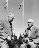 Svenske konsuln t.v. i samtal med postroteman Johan Sjöblom. I
bakgrunden fr.v. Fransilja Haggblom, Olga Gustafsson.