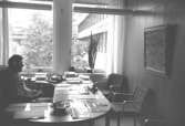 En okänd man sitter vid ett skrivbord i ett kontorrum. Mölndals stadshus, juni 1994.