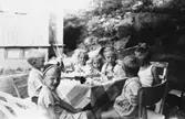 Syskonen Eva (gift Kempe) och Karin (gift Hansson) Pettersson bjuder på saft och tårta i trädgården på Gamlehagsvägen 11 i Torrekulla, 1949. Längst fram från vänster och runt bordet sitter kusinen Göran Pettersson, lekkamraterna Göran Andersson, Britt-Marie Larsson, Karin Pettersson, storasyster Eva Pettersson, kusin Lillemor Pettersson, lekkamrat Christer Andersson.