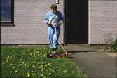 En person klipper gräset utanför en gruppbostad vid Stretereds vårdhem, 1980-talet.