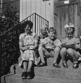 Tre barn och bitr. föreståndare Margit Emilsson (gift Wannerberg -52) sittande på trappan till Krokslätts daghem, Dalhemsgatan 7 i Krokslätt, 1948 - 1951.