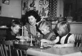Bitr. föreståndare Margit Emilsson (gift Wannerberg -52) sitter tillsammans med två syskon och ett annat barn i 
New look, egenhändigt ritade kläder, Krokslätts daghem år 1949.