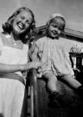 En lärare med ett barn som ska åka rutschkana på Krokslätts daghem, Dalhemsgatan 7 i Krokslätt. 
Under Margit Emilssons (gift Wannerberg -52) praktik som biträde
1945-10-01 - 1946-08-01.