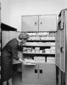 Fru Falk som redogörare tar ut frimärken ur förrådet.