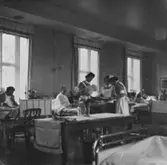 Tre sjuksköterskor delar ut mat på Sabbatsbergs sjukhus i Stockholm, 
cirka 1958. Alltid med nedkavlade ärmar.