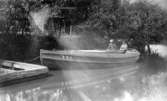 Två män sitter i bogserbåten EVE i Mölndalsån, okänt årtal. Bogserbåten drog kokspråmar.
