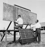 Limhamns skytteförbunds ordförande G. Hagström, förser
Malmöklubbens ordförande Kjell Carlsson med resultat till
finalanslagstavlan.