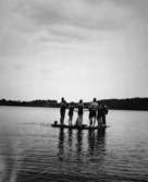 Flera personer vid/på en flotte i Tulebosjön, 1930-tal. Karl Alberts hade ett förråd i Tulebo där byggvirke från firman förvarades. Detta användes av sönerna till olika aktiviteter - bl.a att bygga flottar. Familjen Alberts höll ofta på med olika aktiviteter. På vintrarna åkte man åkte skridskor med segel och fick upp snabb fart. Ibland spelades bandy på sjön. Karl Alberts söner var med i Kållereds bandylag som startade 1938.