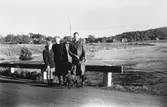 Ett barn, en kvinna och en man står med en hund i koppel vid en grusväg.
Sommar i Lindome i början av 1940-talet.