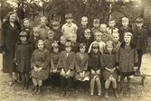 Skolfröken fröken Lundgren med skolklass från Grevedämmets skola, år 1926.
Barnen står vända mot skolan, bakgrunden vetter mot 