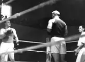 Tungviktsmästare Henry Nicklasson, bosatt i Mölndal, i boxningsmatch mot okänd motståndare, även domare och publik i bakgrunden. HN tillhörde Mölndals Boxningsklubb, och senare Redbergslids.