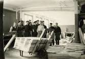 En samling män uppställda för fotografering vid ramverkstaden på Papyrus.

Birger Andersson (1909-2004), tvåa från vänster, arbetade på Papyrus mellan 1924-1976. Hans arbetsplats var ramverkstaden där de spikade lastpallar och 